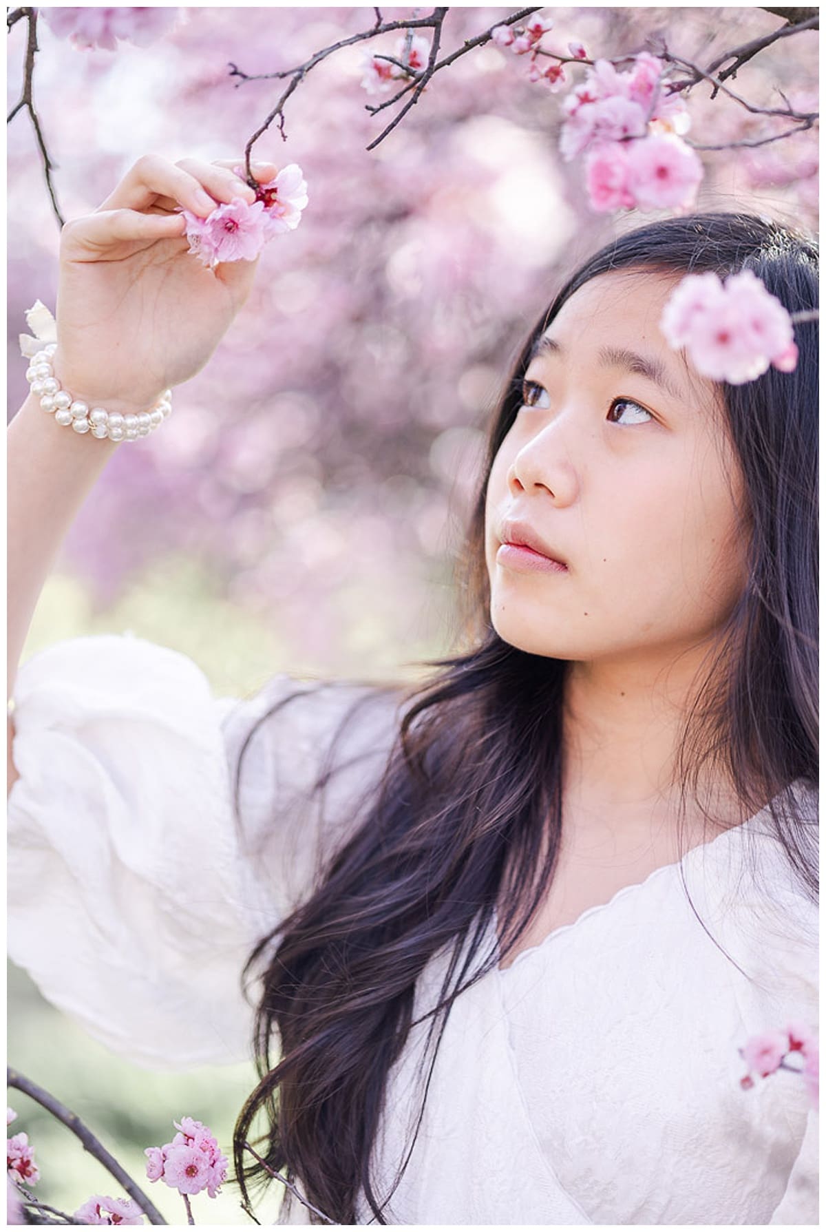 girl looking at and holding the pink plum blossoms