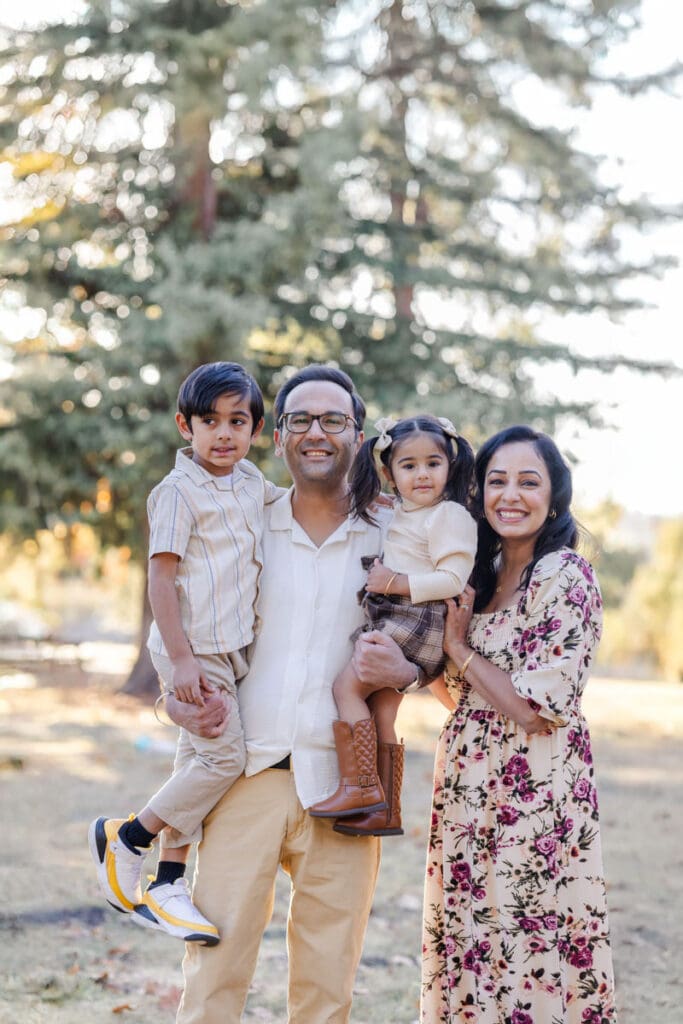 A smiling family of four pose during their fall family photoshoot at Ed Levin County Park, Milpitas