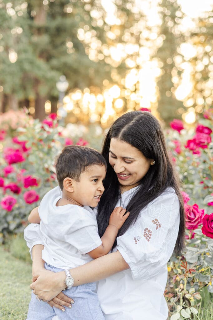 Mom and her toddler son lovingly hug each other during their photoshoot in the blooming rose garden in San Jose