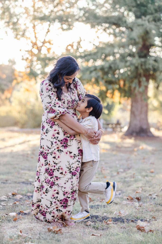 Mom and young son hugging each other with mom looking down lovingly at her son during a fall family photoshoot