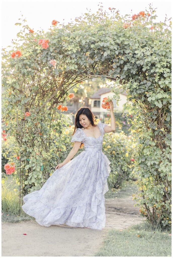 Mom poses with a beautiful flowy outfit surrounded by roses at the rose garden
