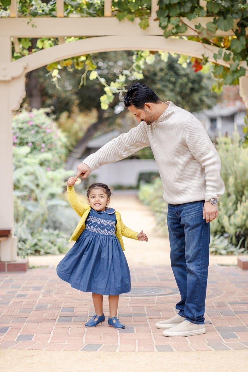 Dad twirls toddler girl under the gazebo in a fall photoshoot at Palo Alto